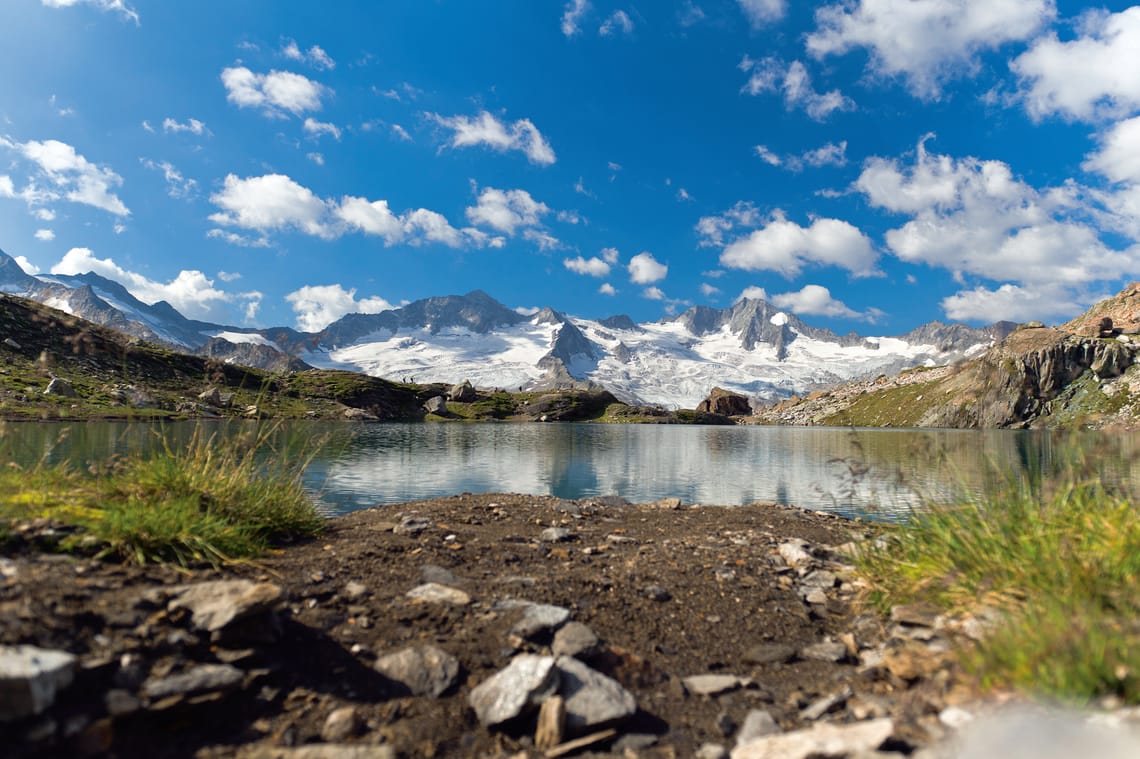 Berliner Höhenweg Blick auf den Berliner Höhenweg im Zillertal: klarer Bergsee, schneebedeckte Gipfel und blauer Himmel – perfekte Kulisse für eine Hüttenwanderung ab Mayrhofen.
