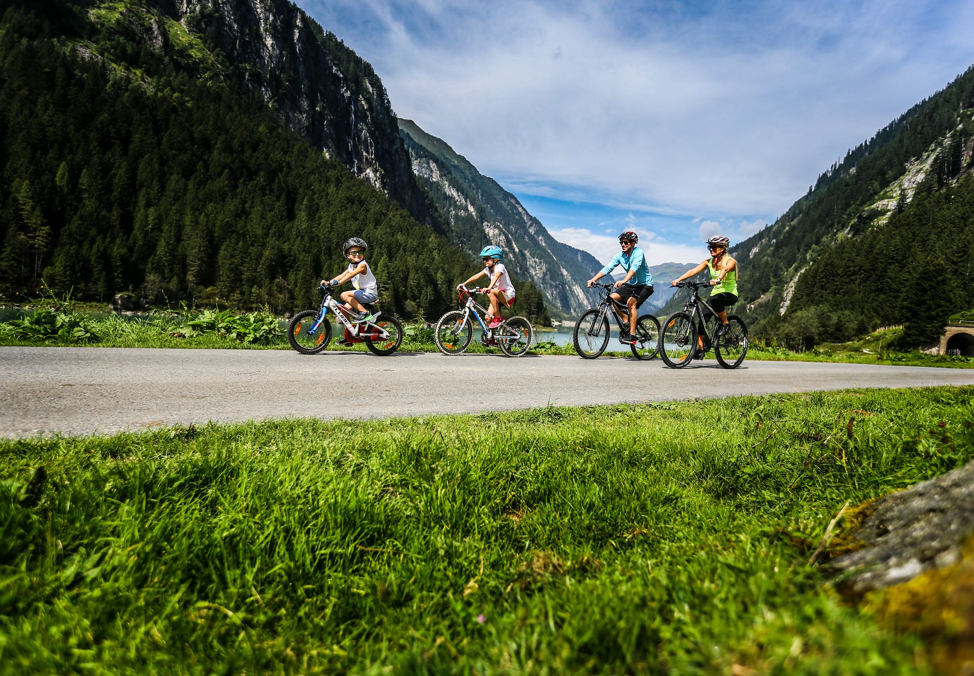 Family bike tour in the Stilluptal A family with children cycling in the Stillup Valley near Mayrhofen in the Zillertal, along a cycle path through the alpine countryside and mountain landscape.