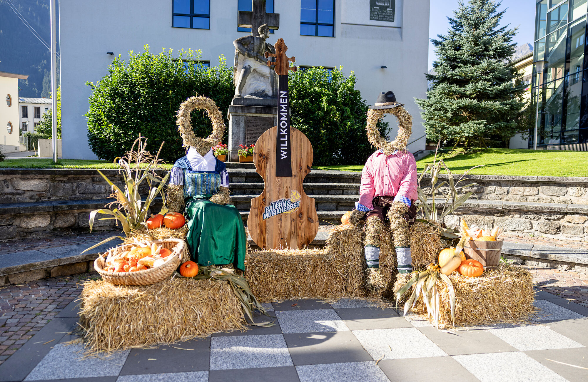 Fotopoint beim Zillertaler Bauern- und Musikherbst: zwei Heupuppen in Tracht zwischen Heuballen, Kürbissen und herbstlicher Dekoration vor einer traditionellen Bauernhof-Kulisse.