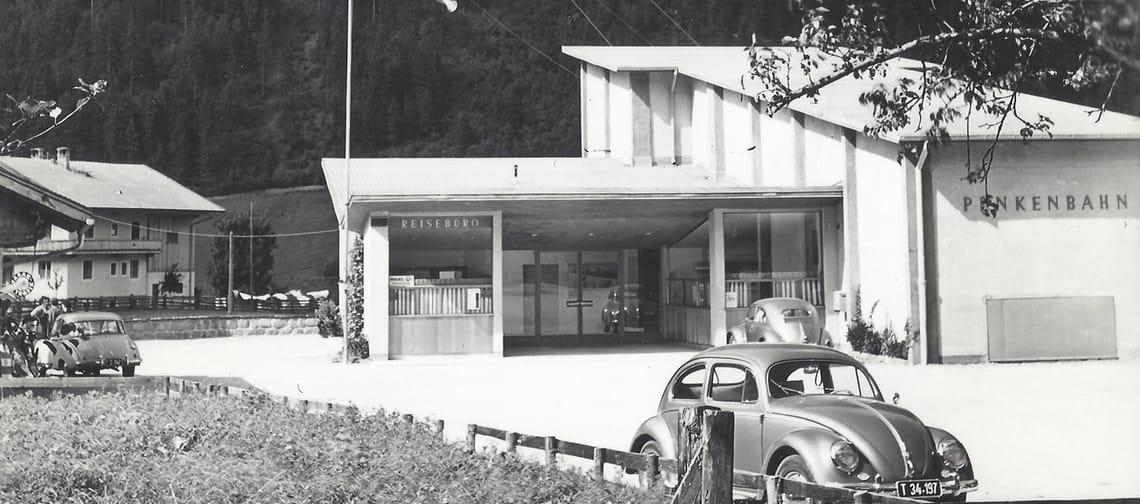 Schwarz-weiß-Foto eines Bahnhofs mit Autos und einem Gebäude, Beschriftung: Penkenbahn Mayrhofen, Tirol.