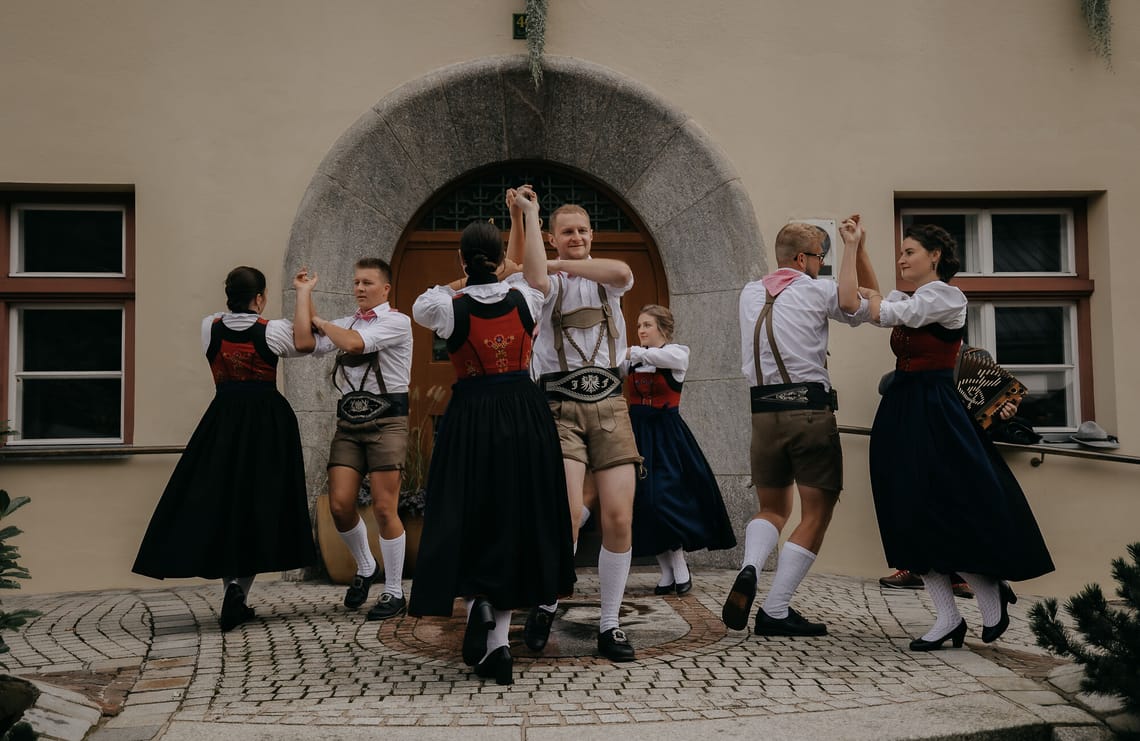 VolXtonza Schuhplattler | Zillertaler Bauern- und Musikherbst Schuhplattler-Gruppe VolXtonza beim Zillertaler Bauern- und Musikherbst: Frauen und Männer in traditioneller Tracht tanzen gemeinsam vor einem historischen Gebäude.