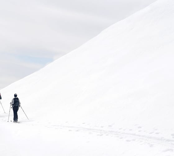 Two people walking in the snow on a ski tour