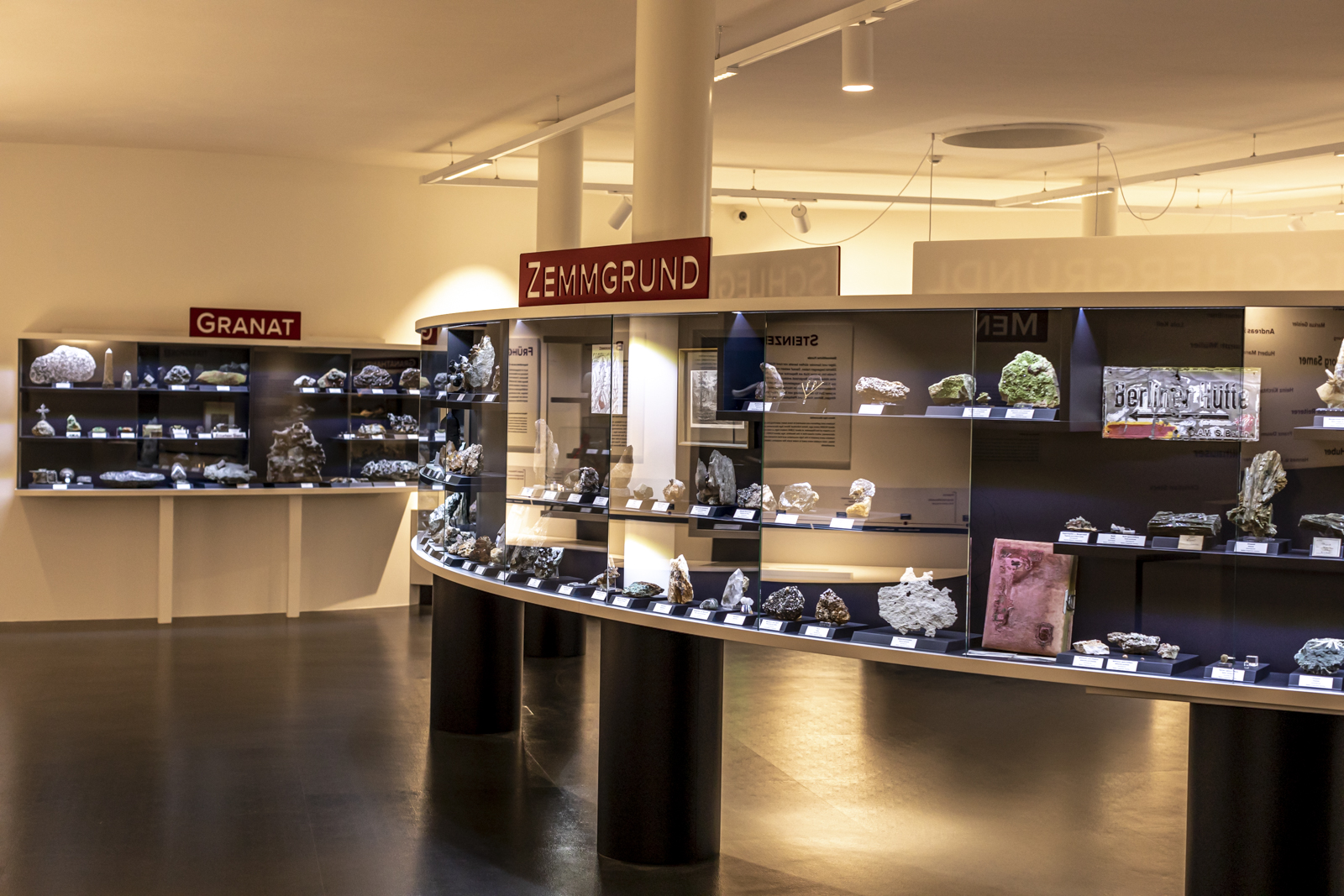 View of the "Hidden Treasures" exhibition at the Ginzling Nature Park House in the Mayrhofen-Hippach holiday region, Zillertal. Elegantly lit display cases showcase minerals and rock finds from the region.
