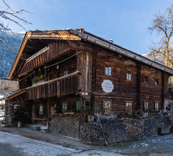 Das Bild zeigt das Strasserhäusl im Winter von außen mit einem blauen Himmel im Hintergrund.