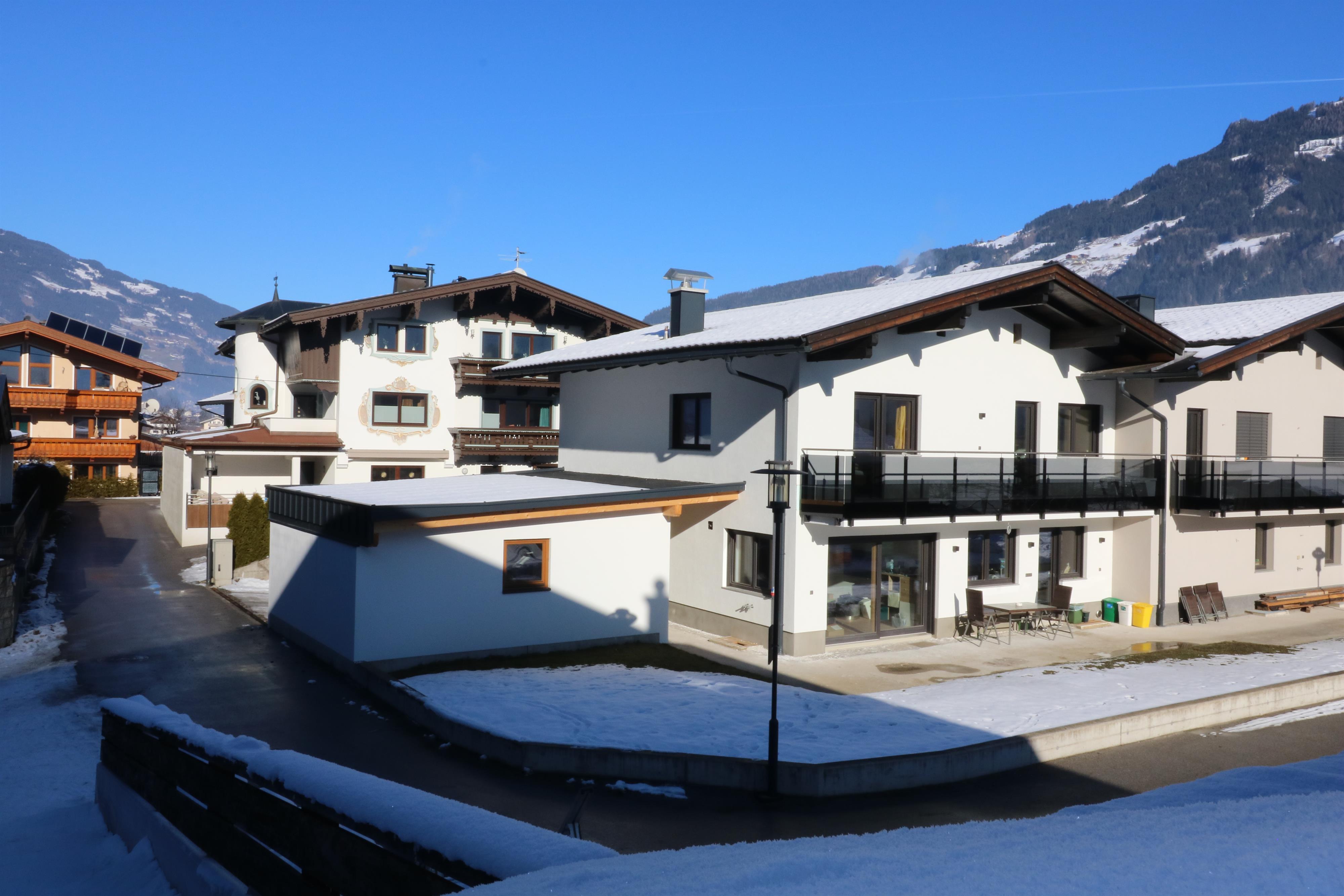 Modern houses in a snowy mountain area under a clear blue sky.