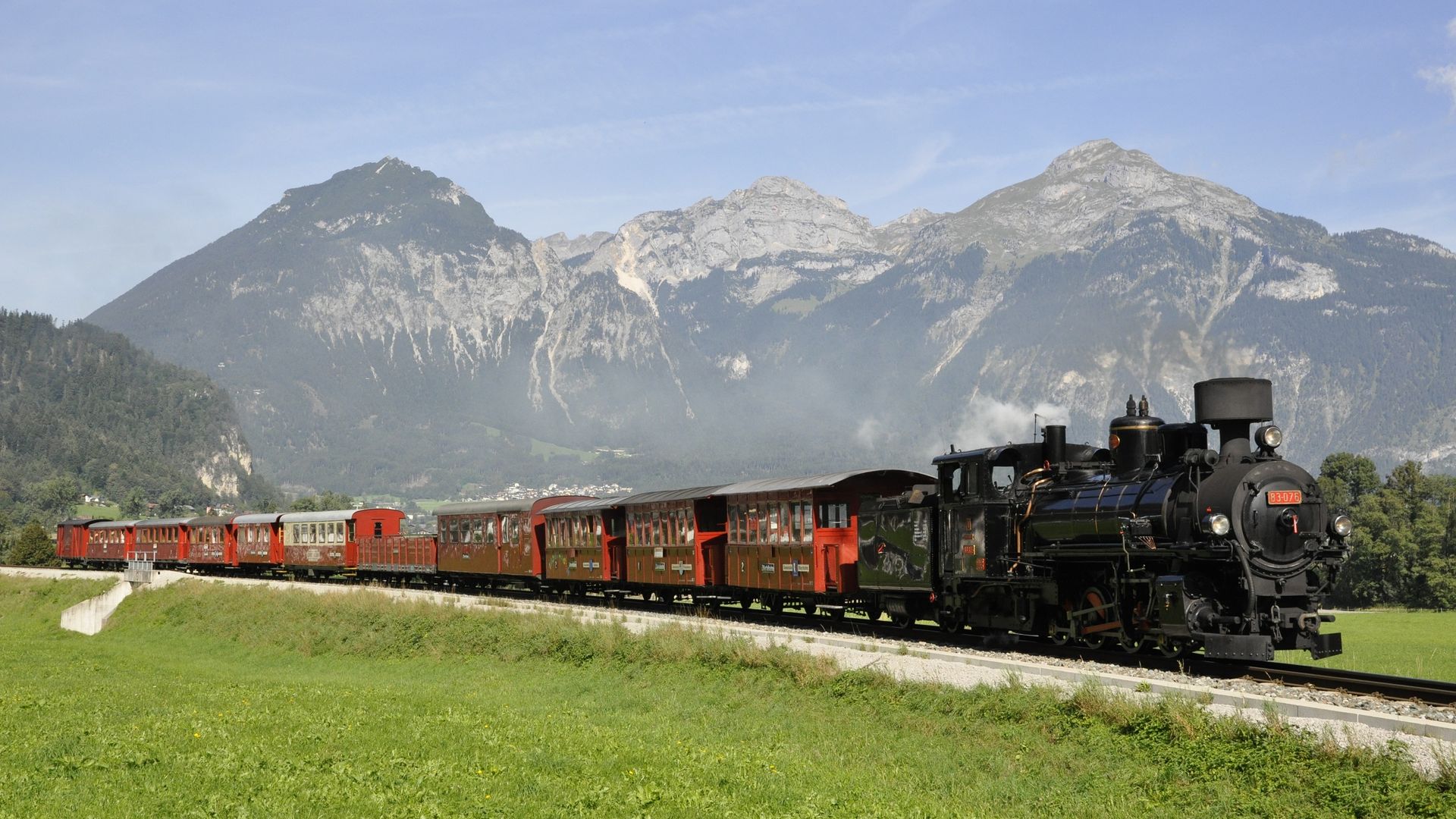 „Ein nostalgischer Dampfzug der Zillertalbahn fährt durch grüne Wiesen vor imposanter Bergkulisse – ein Highlight für Jung und Alt im Zillertal.