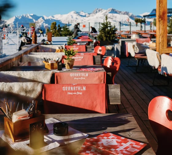 Das Bild zeigt die Granatalm Terrasse mit dekorierten Tischen und einer Bergkulisse mit blauem Himmel im Hintergrund.
