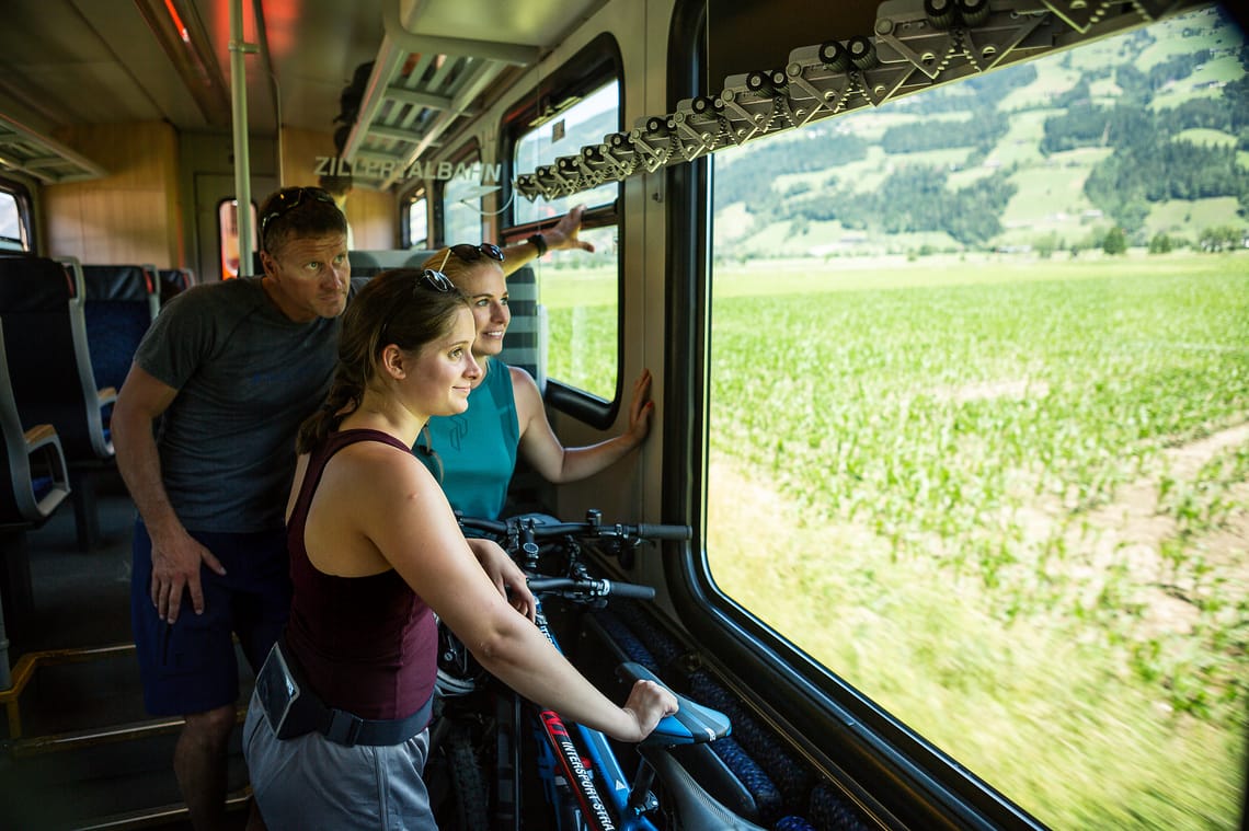 Discovery tour with the Zillertalbahn On the train through the Zillertal: two people with bicycles look out of the window onto green fields and hills. Bicycle transport on the train makes for a comfortable and environmentally friendly journey along the Zillertal Cycle Path.