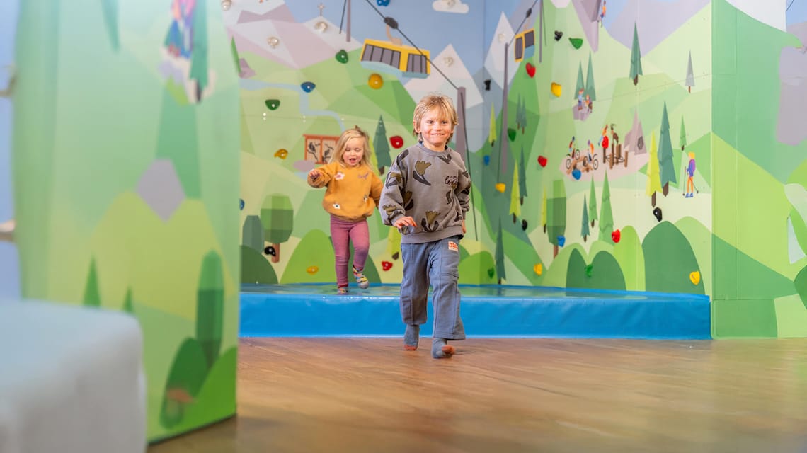 Kids are playing in front of the big climbing wall at the AlbertAdler PlayWorld by Ravensburger on Mount Ahorn