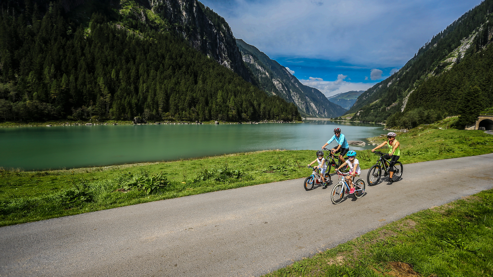 Biken mit der Familie in Mayrhofen-Hippach Familie beim Radfahren im Stilluptal bei Mayrhofen im Zillertal auf einem Radweg entlang des Flusses mit Blick auf Berge und Natur