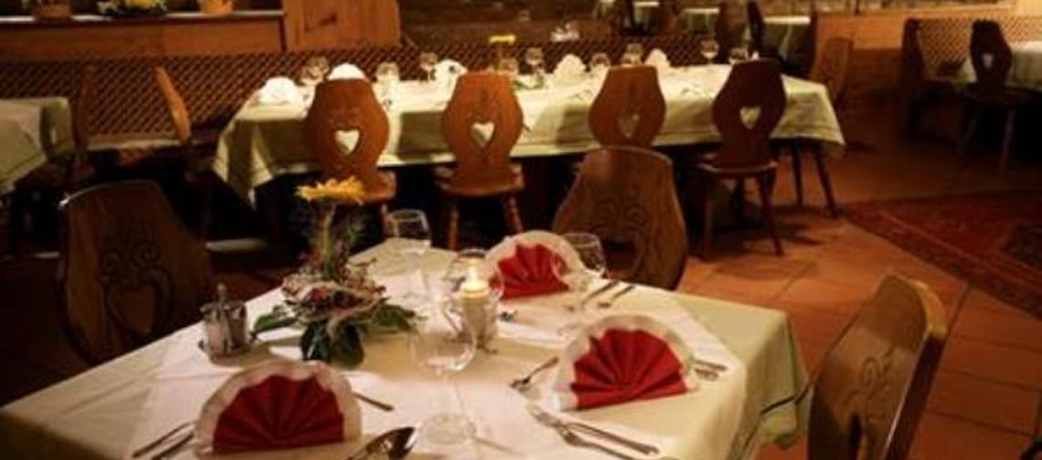 Der Speiseraum wirkt traditionell und gemütlich – die Tische sind bereits eingedeckt, auf dem Boden liegen orangefarbene Fliesen, die dem Raum einen warmen Ton verleihen