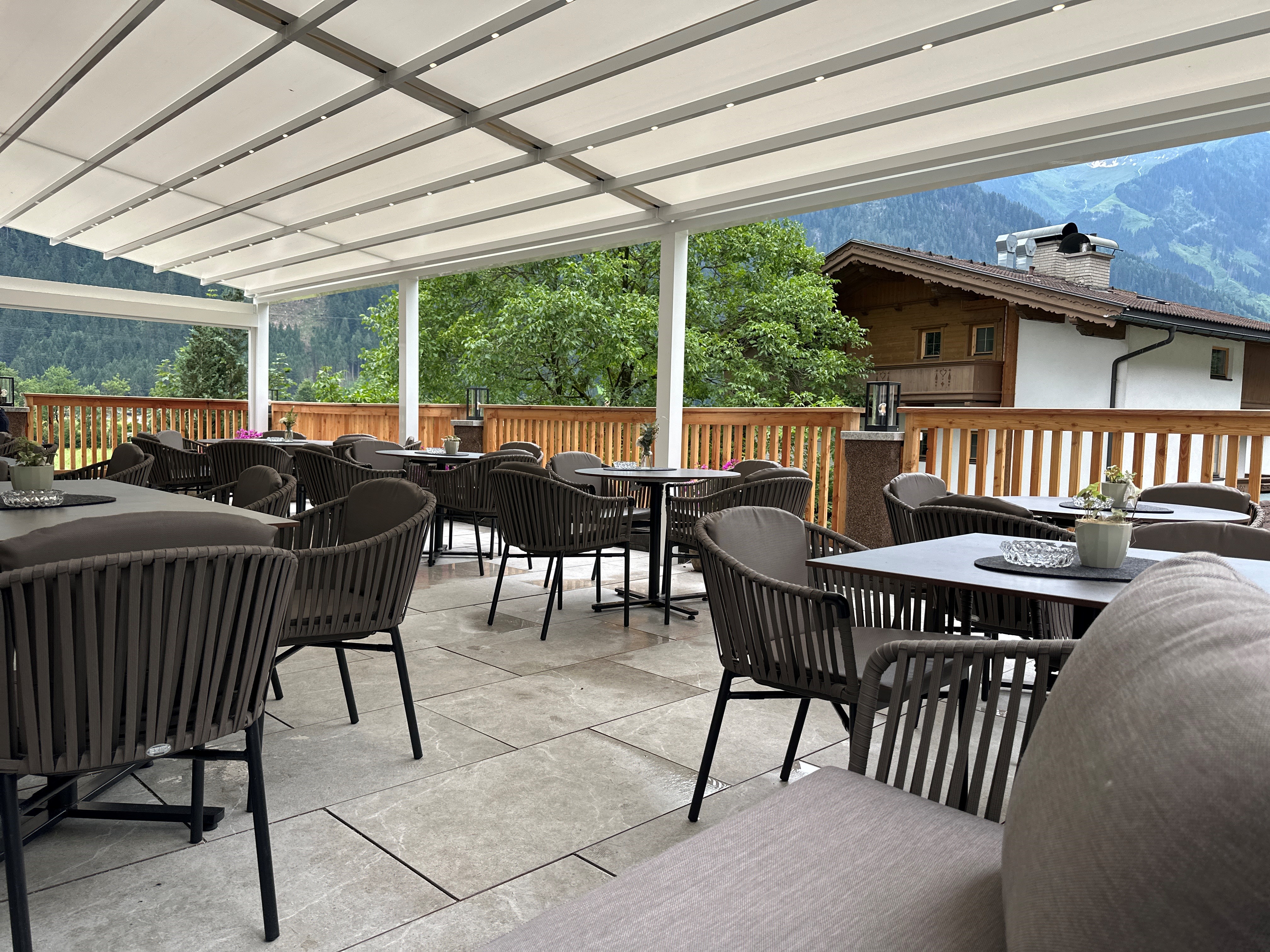 Schwarze Stühle und Tische auf einer Terrasse mit einer weißen Überdachung