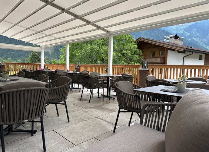 Schwarze Stühle und Tische auf einer Terrasse mit einer weißen Überdachung