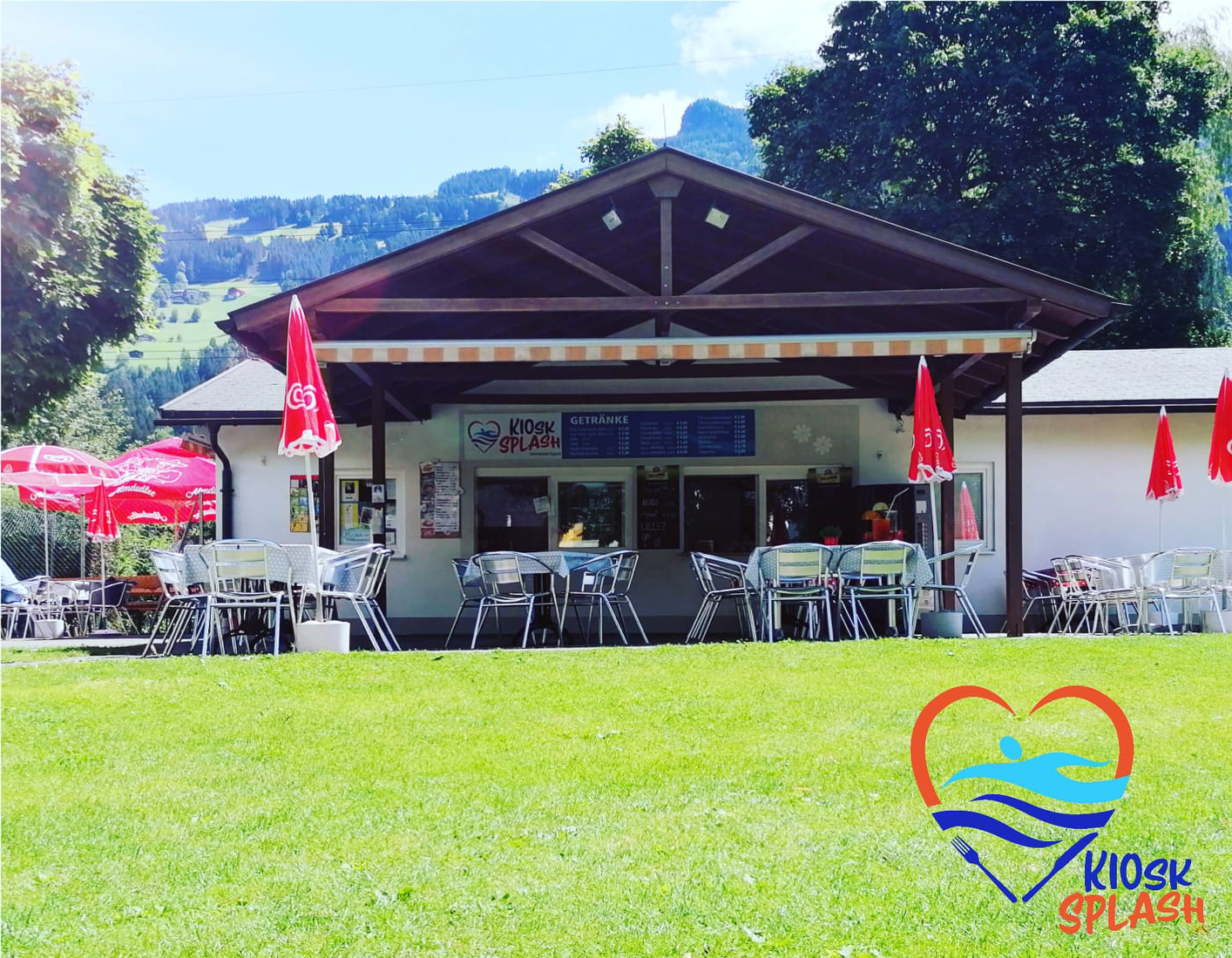 Kiosk im Freischwimmbad Hippach mit Sitzbereich auf grüner Liegewiese bei Sonnenschein. Beliebter Treffpunkt für Snacks und Erfrischungen im Sommer mit Blick auf die Alpen.