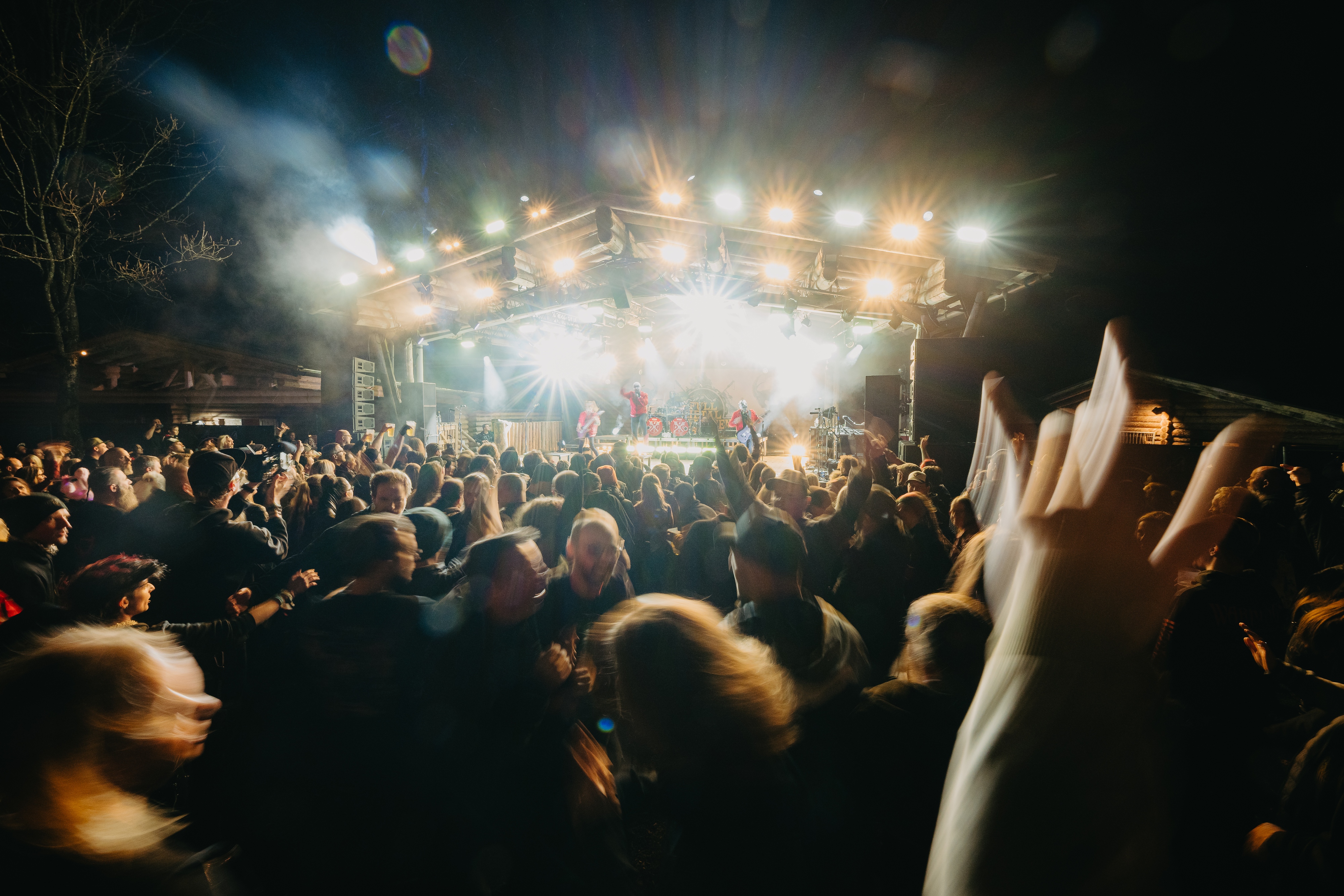 Konzertpublikum vor einer beleuchteten Bühne beim Full Metal Mayrhofen, mit erhobenen Händen und dichter Festivalatmosphäre. Metal-Konzert bei Nacht in alpiner Umgebung in Mayrhofen.