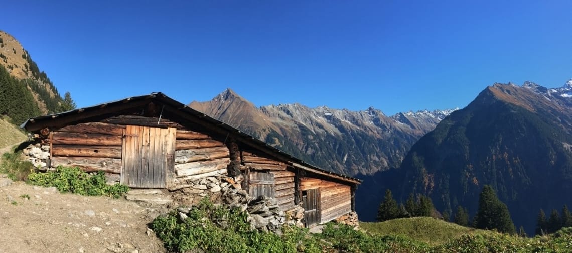 Eine alte Berghütte mit Berge im Hintergrund