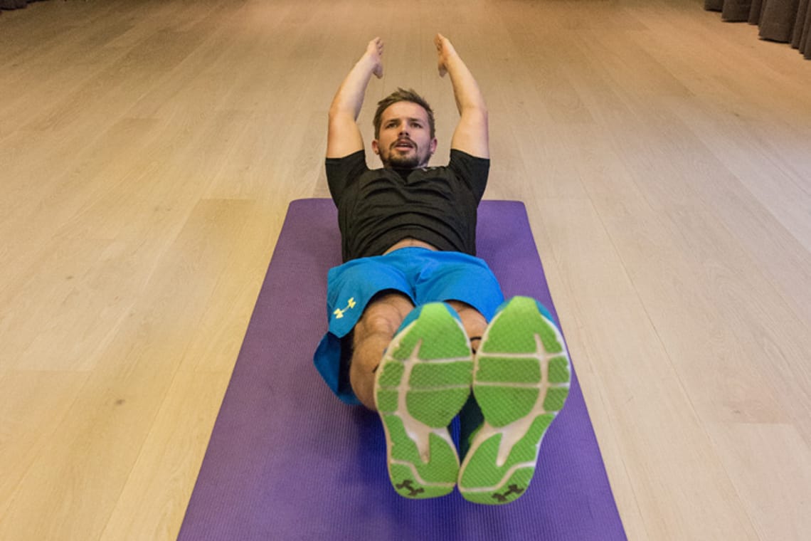 Hollow Position - Chris Ebenbichler Man performing hollow position exercise on yoga mat in training hall in Mayrhofen. Christoph Ebenbichler demonstrates core and stability training for ski fitness – get fit for winter.