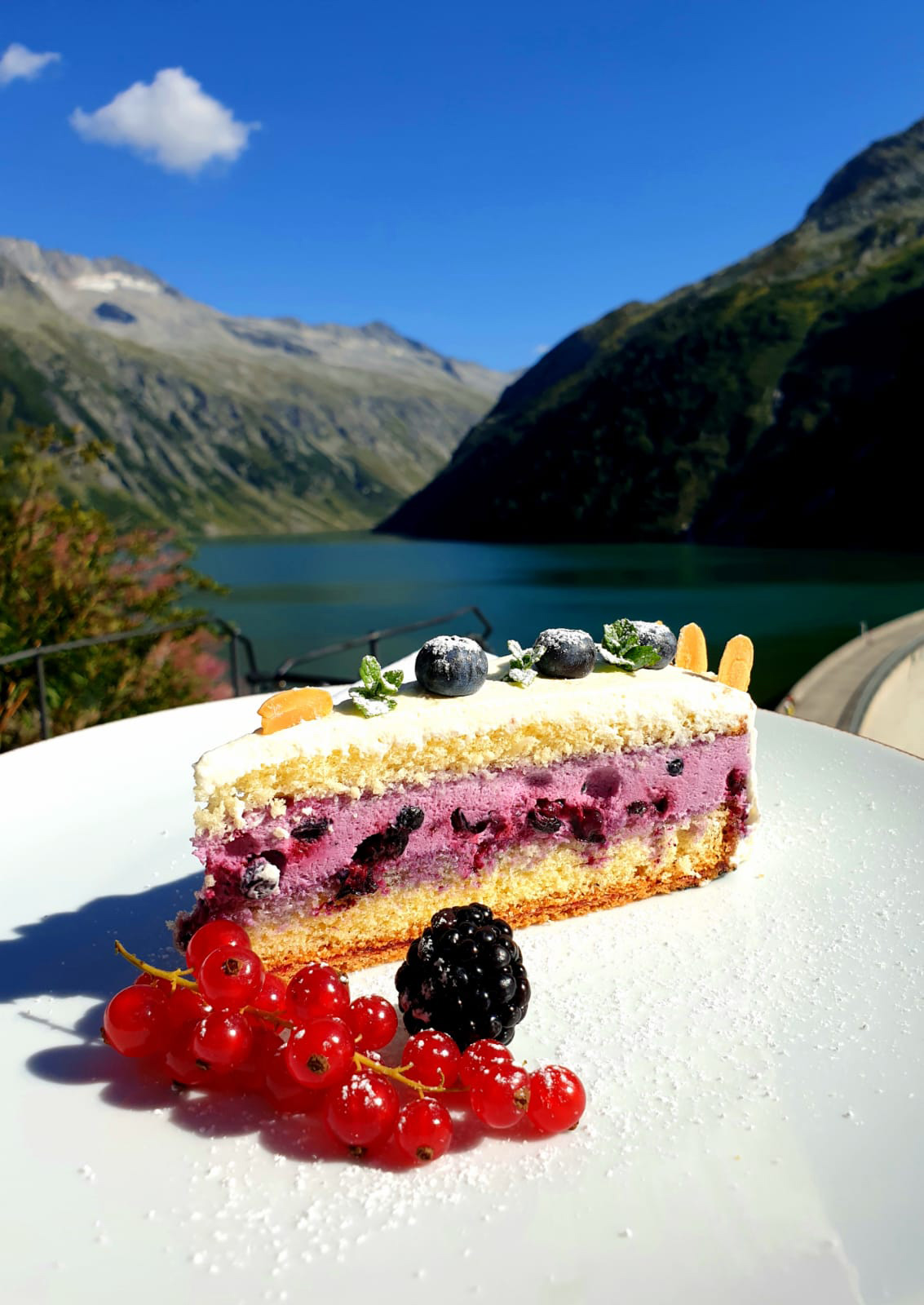 Dessert mit Beeren auf der Terrasse des Adlerblick im Zillergrund bei Mayrhofen, serviert vor dem Blick auf den Speicher Zillergründl und die umliegende Berglandschaft – Genussherbst-Partnerbetrieb.