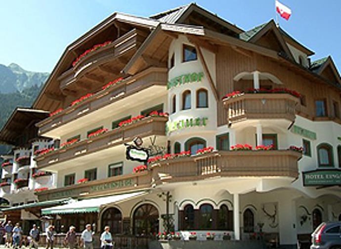 The picture shows Gasthof Perauer from the outside. Above the building stretches a clear blue sky, giving the scene a friendly and bright atmosphere.