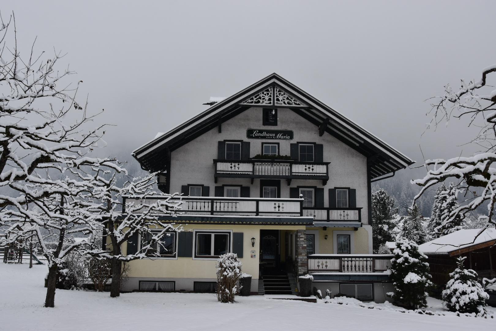 A multi-story house with snow-covered trees and garden, labeled 'Landhaus Maria'.