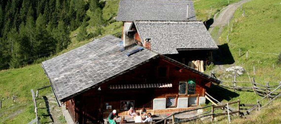 Cabins in the mountains with people sitting outside on a patio.