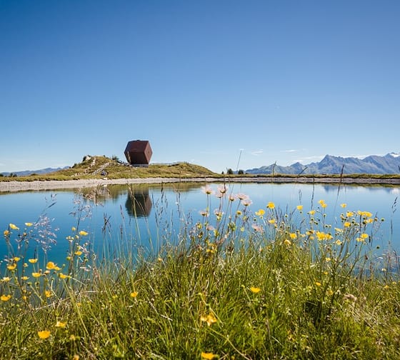 Das Bild zeigt die Granatalm am Penkenjoch mit einem Speichersee im Vordergrund.