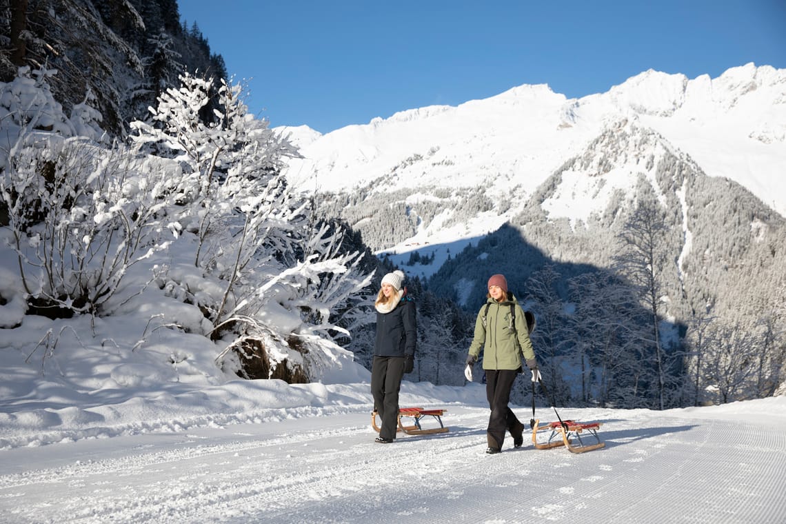 Rodelbahn Tristenbachalm Zwei Personen ziehen ihre Rodel auf der Rodelbahn Tristenbachalm bei Ginzling im Zillertal