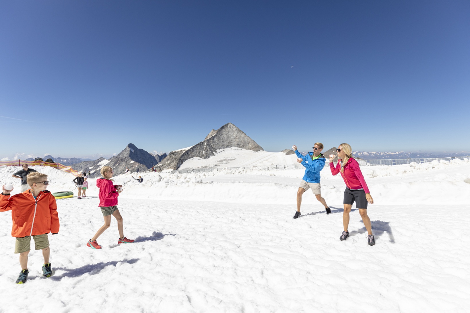 Familie macht eine Schneeballschlacht in kurzen Hosen, im Sommer, auf 3.250m am Hintertuxer Gletscher