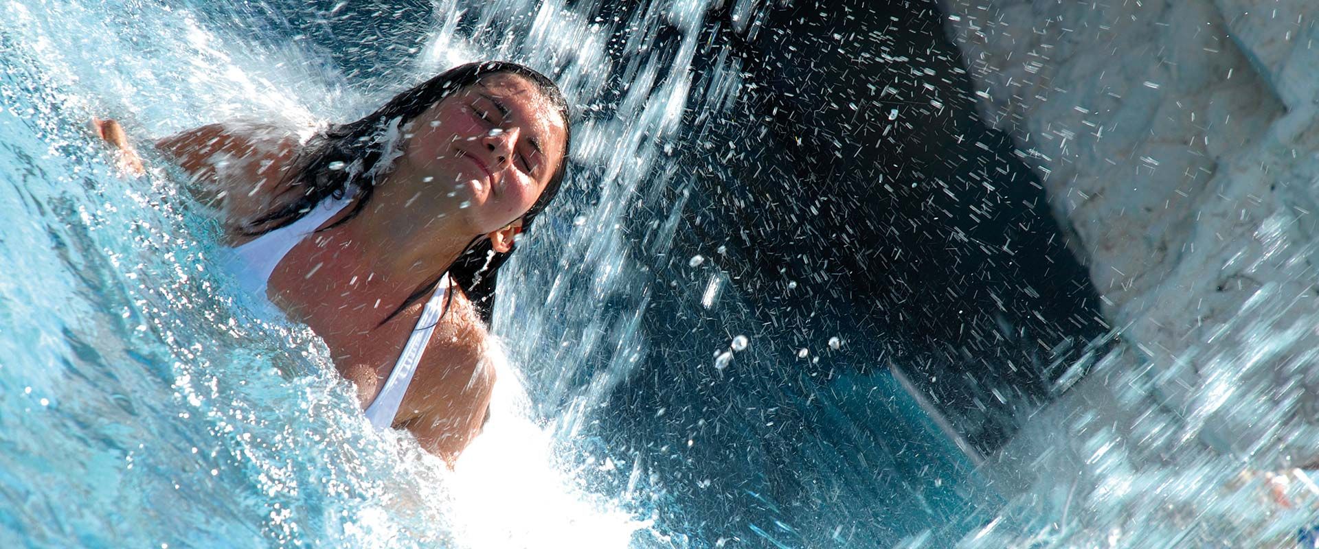Woman enjoying the refreshing water at the Erlebnisbad Mayrhofen in the Zillertal – fun and relaxation surrounded by the Tyrolean mountains.