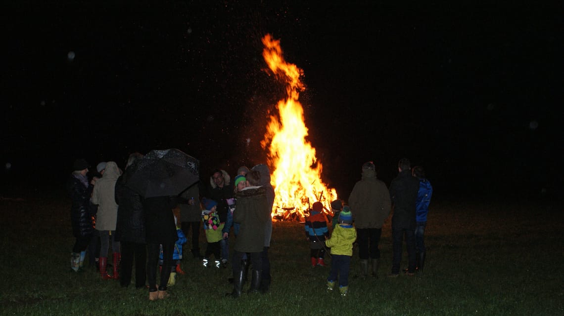 Osterfeuer in Mayrhofen-Hippach Menschen stehen in einem Kreis um ein hell loderndes Osterfeuer in Mayrhofen, Zillertal. Groß und Klein blicken in die Flammen, die die dunkle Nacht erhellen. Der traditionelle Brauch bringt die Gemeinschaft zusammen.