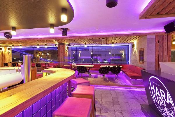 The image shows the Harakiri Bar illuminated by modern pink LED lights, creating a stylish and energetic ambiance.