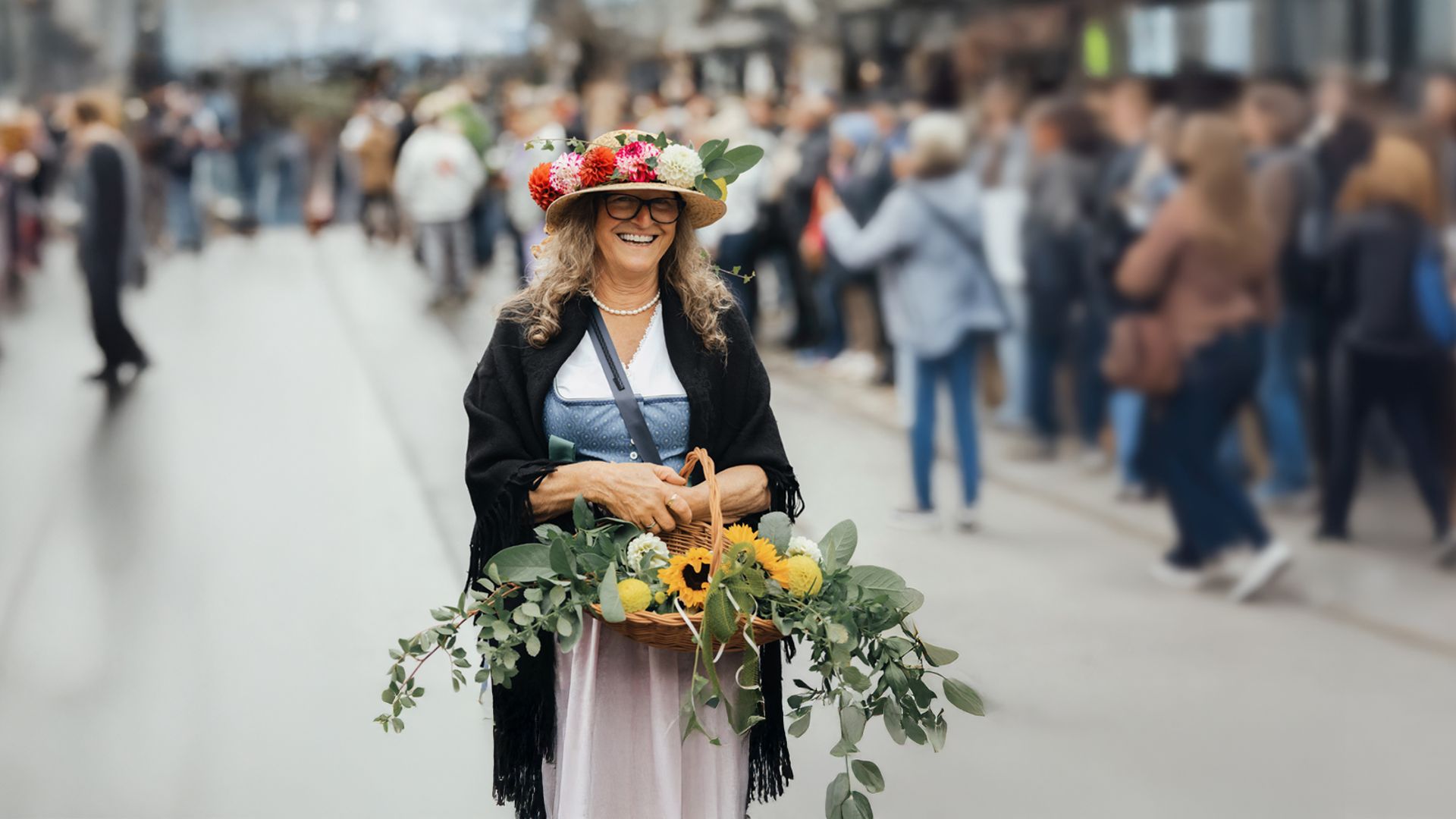 Frau im Dirndl mit Blumenkranz und Erntekorb auf einer belebten Straße beim Zillertaler Bauern- und Musikherbst in Mayrhofen.Frau im Dirndl mit Blumenkranz und Erntekorb auf einer belebten Straße beim Zillertaler Bauern- und Musikherbst in Mayrhofen.
