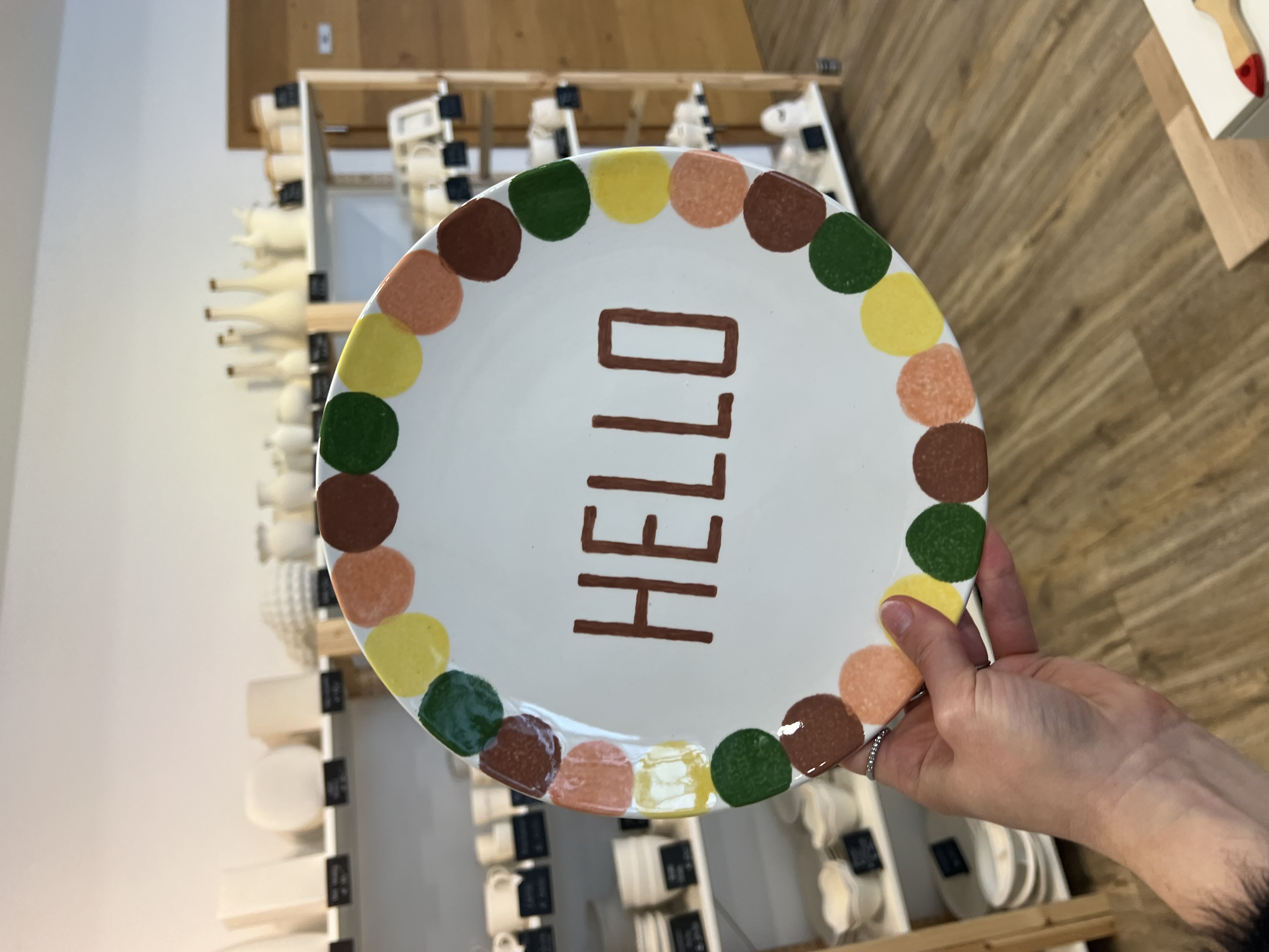 Ein Teller auf dem Hello steht und der am Rand mit bunten Punkten verziert ist