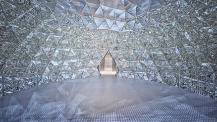 Interior of a futuristic mirrored building with geometric patterns and reflective surfaces.