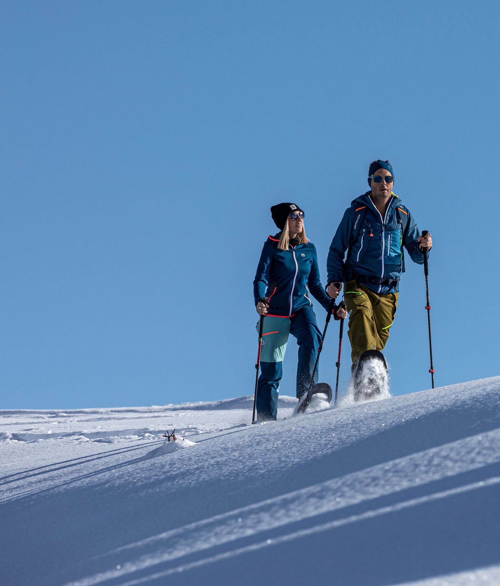 Zwei Personen beim Schneeschuhwandern in Mayrhofen-Hippach auf einem sonnigen Hang mit unberührtem Schnee und Blick in die Winterlandschaft.