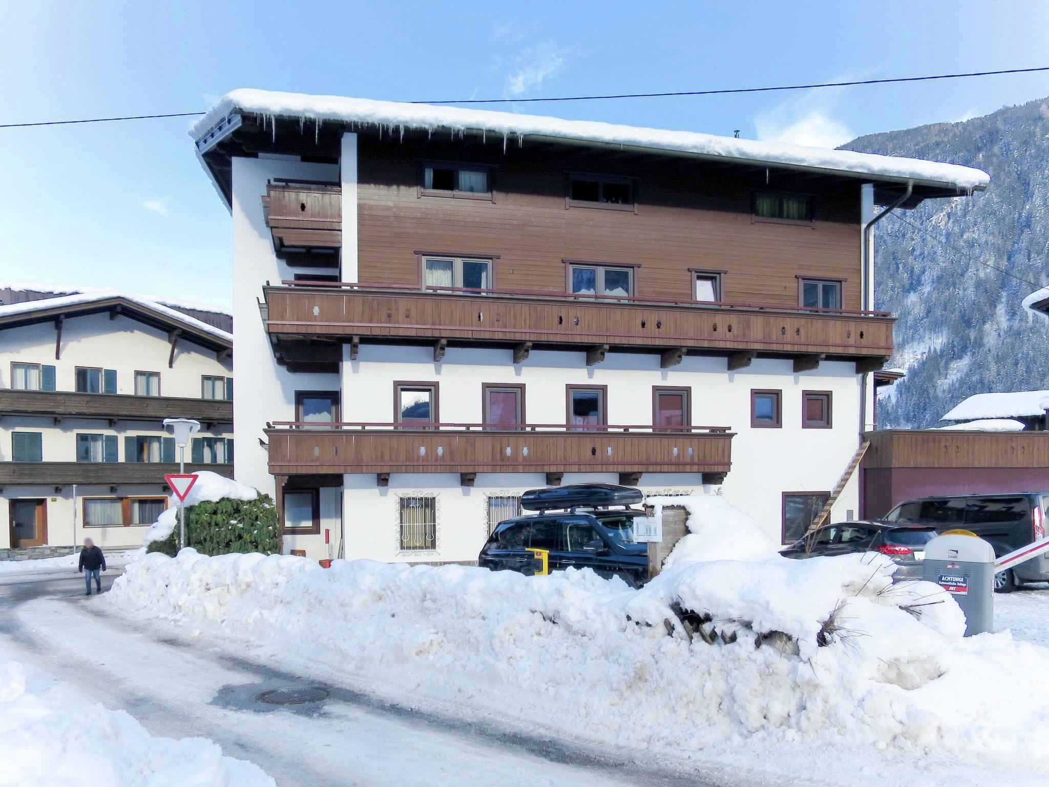 Mehrstöckiges Haus mit Holzfassade, Schneedecke auf dem Dach, im Winter, in einer Bergregion.