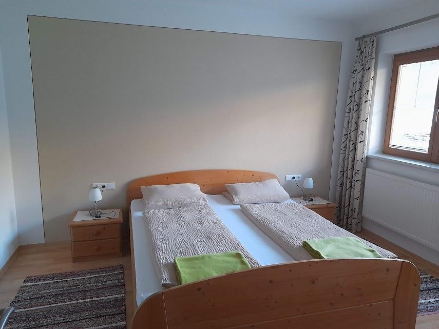 Bedroom with a double bed, two nightstands, lamps, window with curtains, and a rug on the floor.