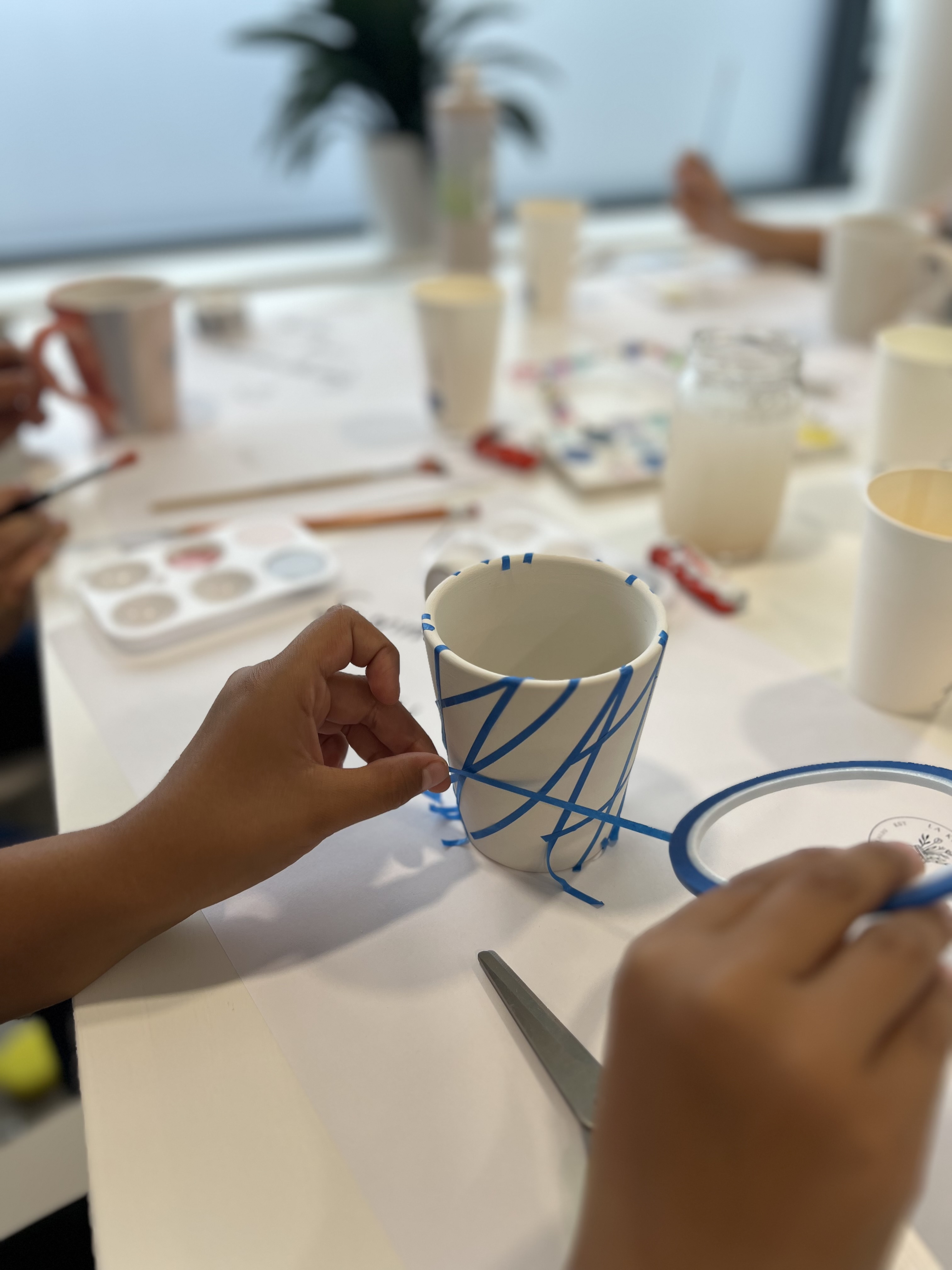 Eine Tasse mit blauem Band abgeklebten Flächen, um diese zu bemalen