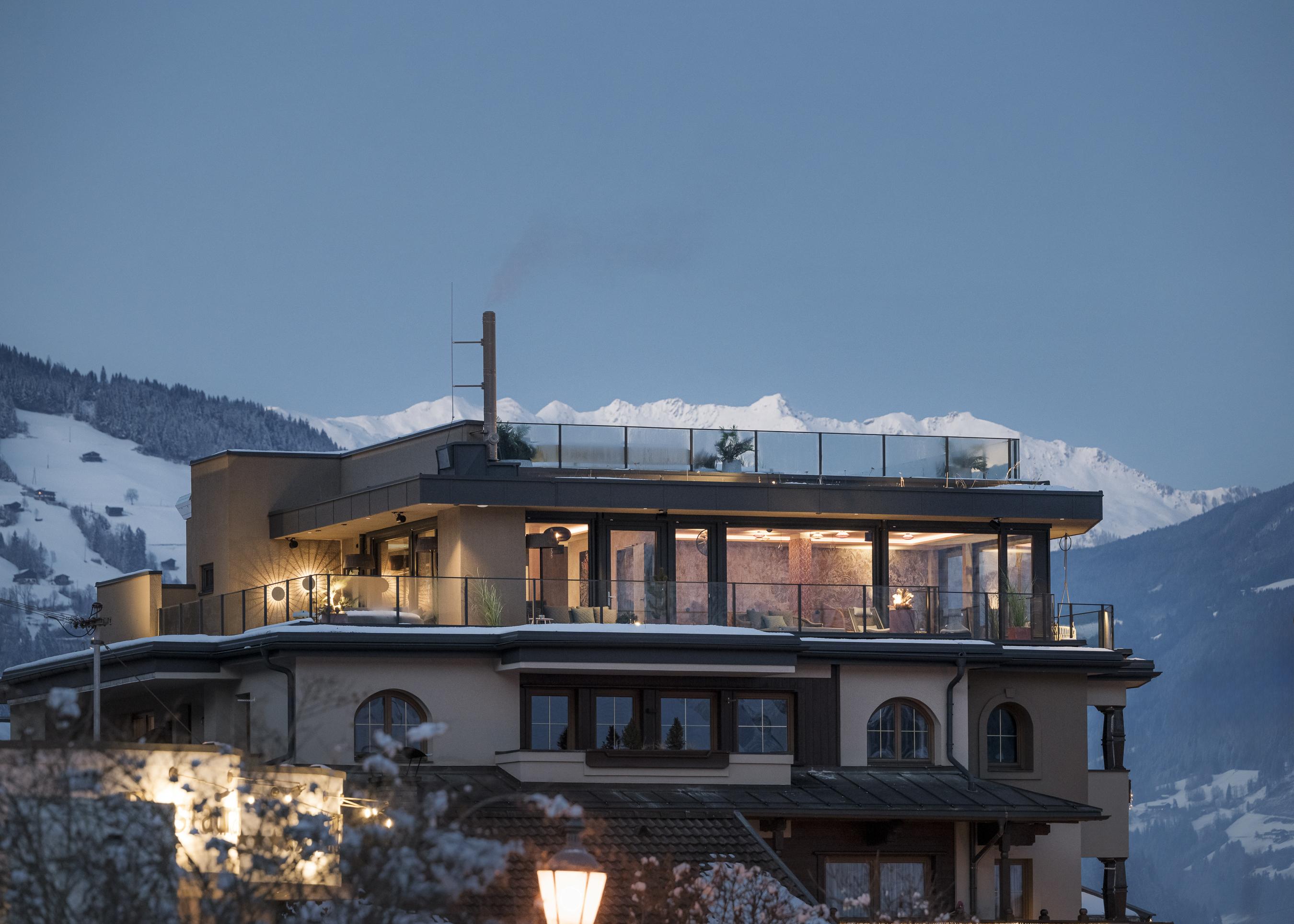 Moderne Wohnung auf einem Balkon mit Blick auf schneebedeckte Berge bei Sonnenuntergang.