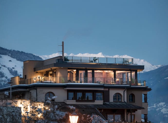 Moderne Wohnung auf einem Balkon mit Blick auf schneebedeckte Berge bei Sonnenuntergang.
