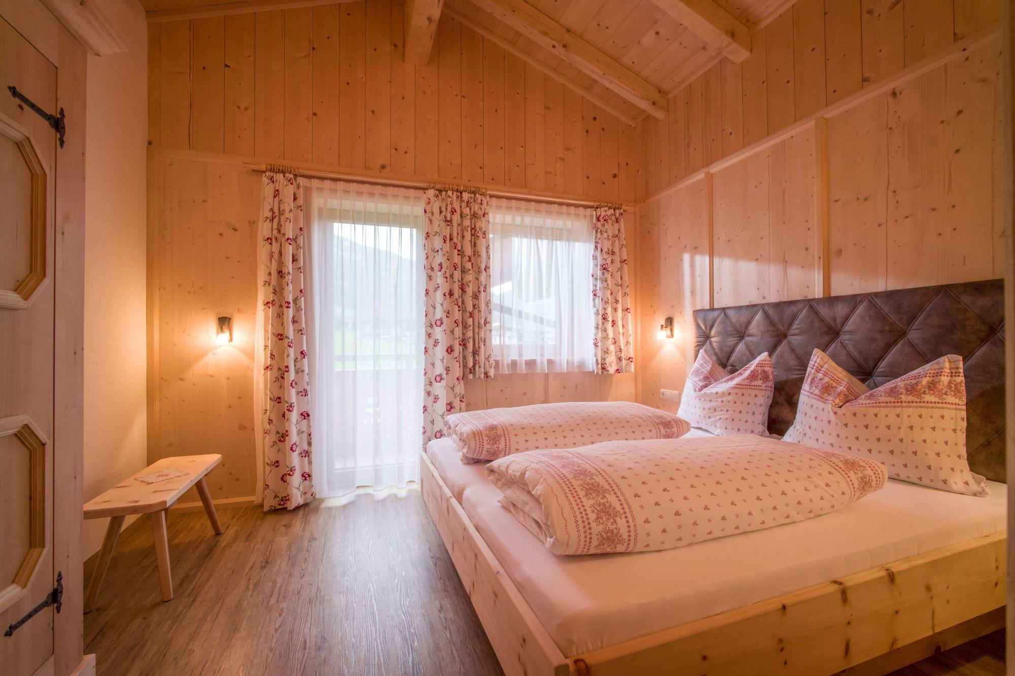 Ein gemütliches Schlafzimmer mit Holzverkleidung, Bett, Vorhängen und weichem Licht, warm und einladend.