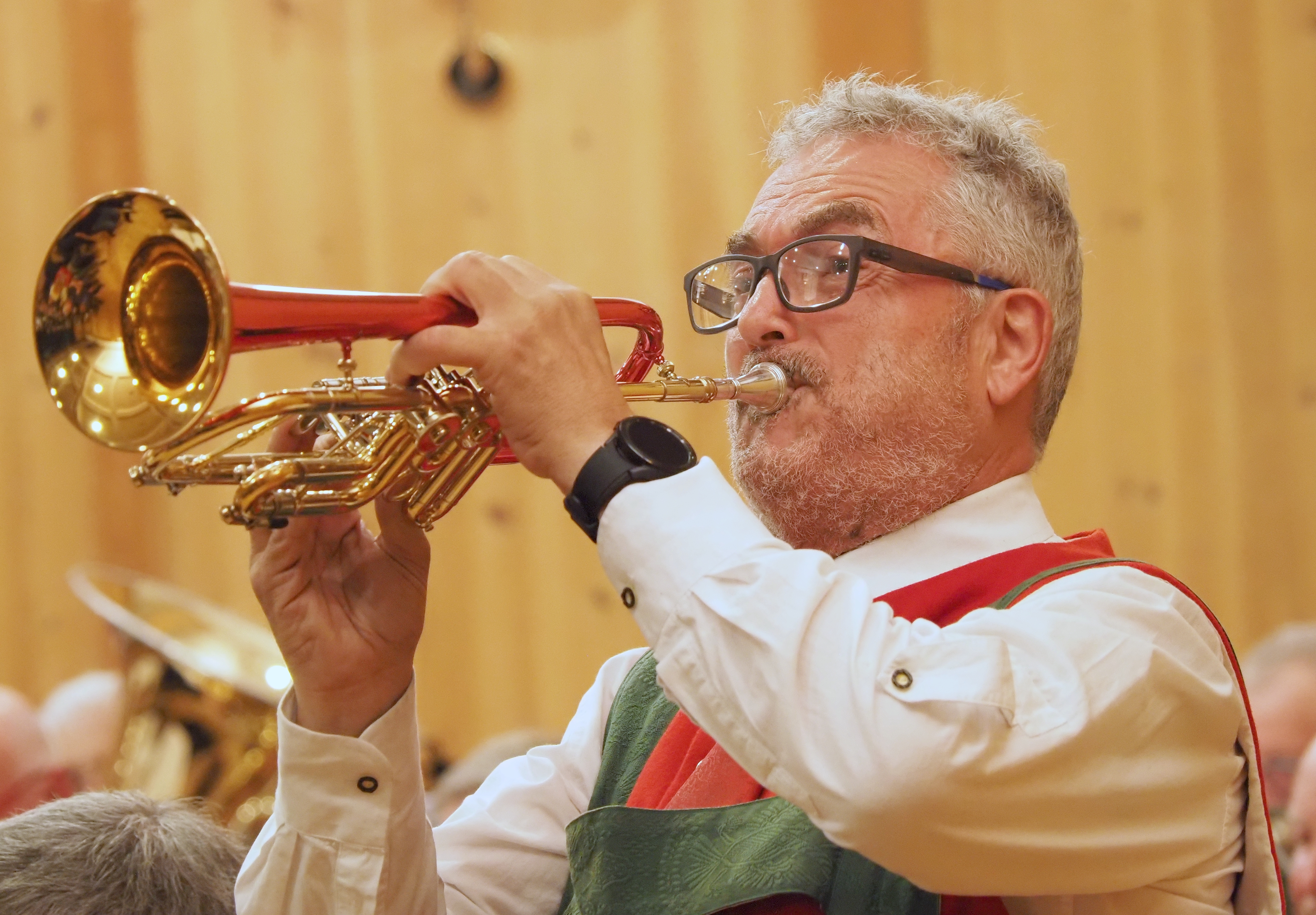Ein Musikant in traditioneller Tiroler Tracht spielt am Flügelhorn.