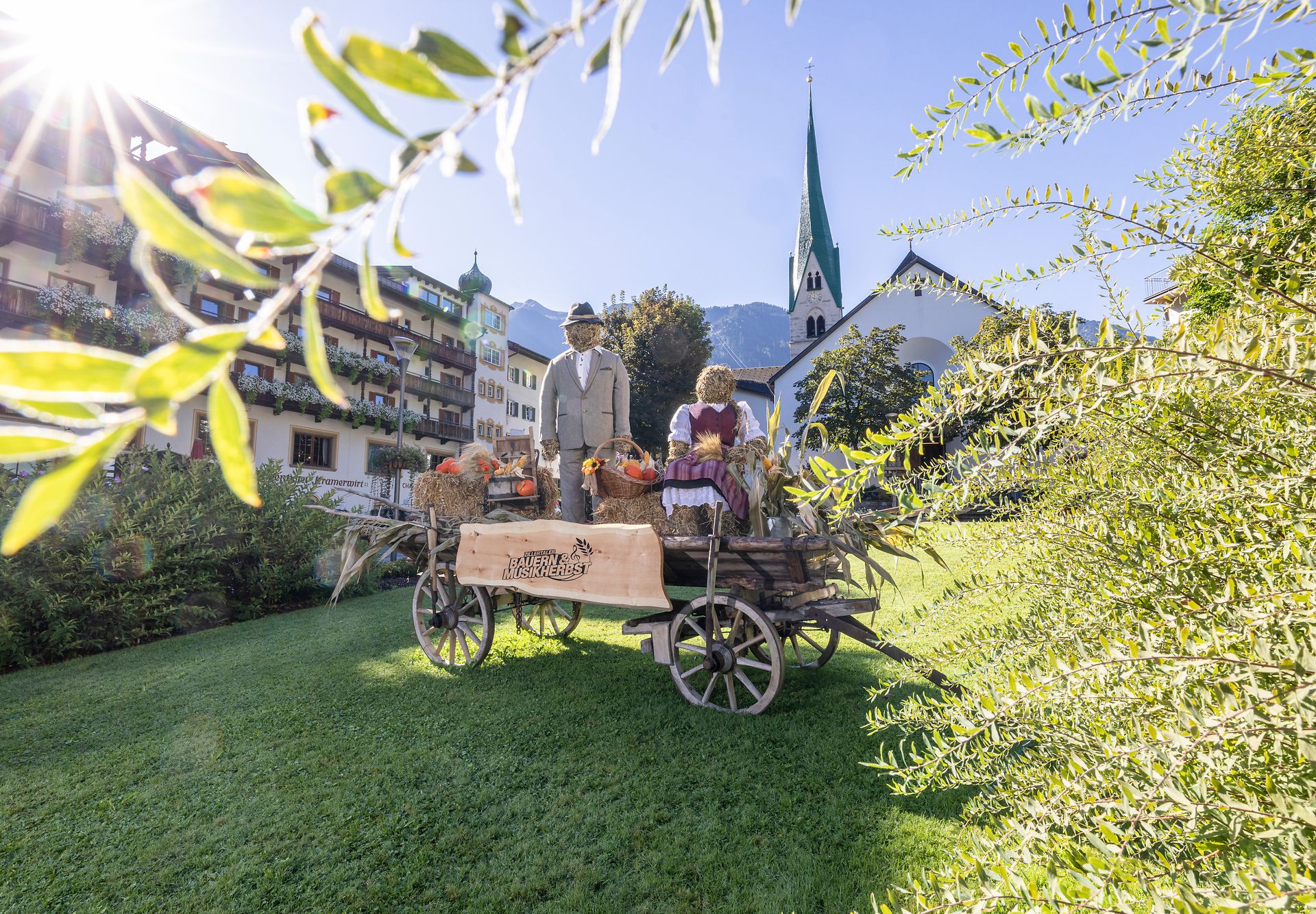 Decorated harvest wagon with straw figures and flowers on a green meadow in Mayrhofen. A symbol of the Zillertal Farmers' and Music Autumn Festival.