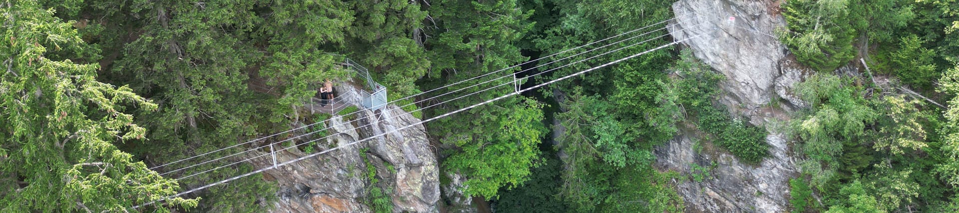 Rope suspension bridge Himmelsbrücke - via ferrata Zimmereben ©Jolanda Guadagnini Aerial view of the Himmelsbrücke rope bridge on the Zimmereben via ferrata in the Mayrhofen-Hippach holiday region, Tyrol – striking rock formations surrounded by dense forest.