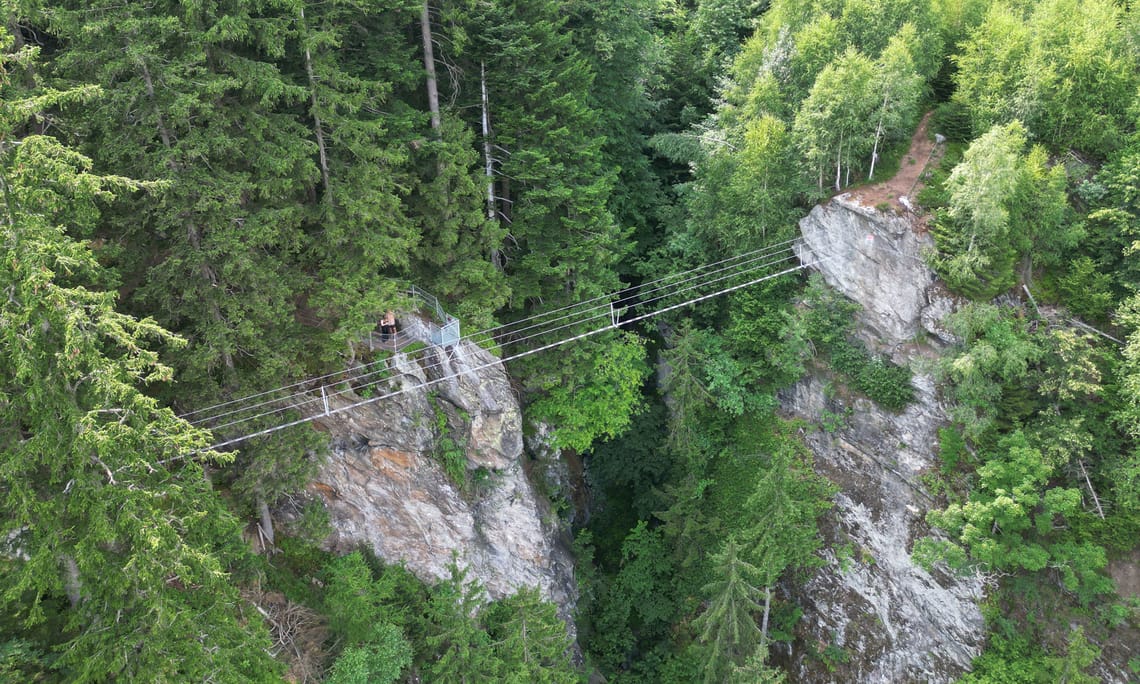 Rope suspension bridge Himmelsbrücke - via ferrata Zimmereben ©Jolanda Guadagnini Aerial view of the Himmelsbrücke rope bridge on the Zimmereben via ferrata in the Mayrhofen-Hippach holiday region, Tyrol – striking rock formations surrounded by dense forest.