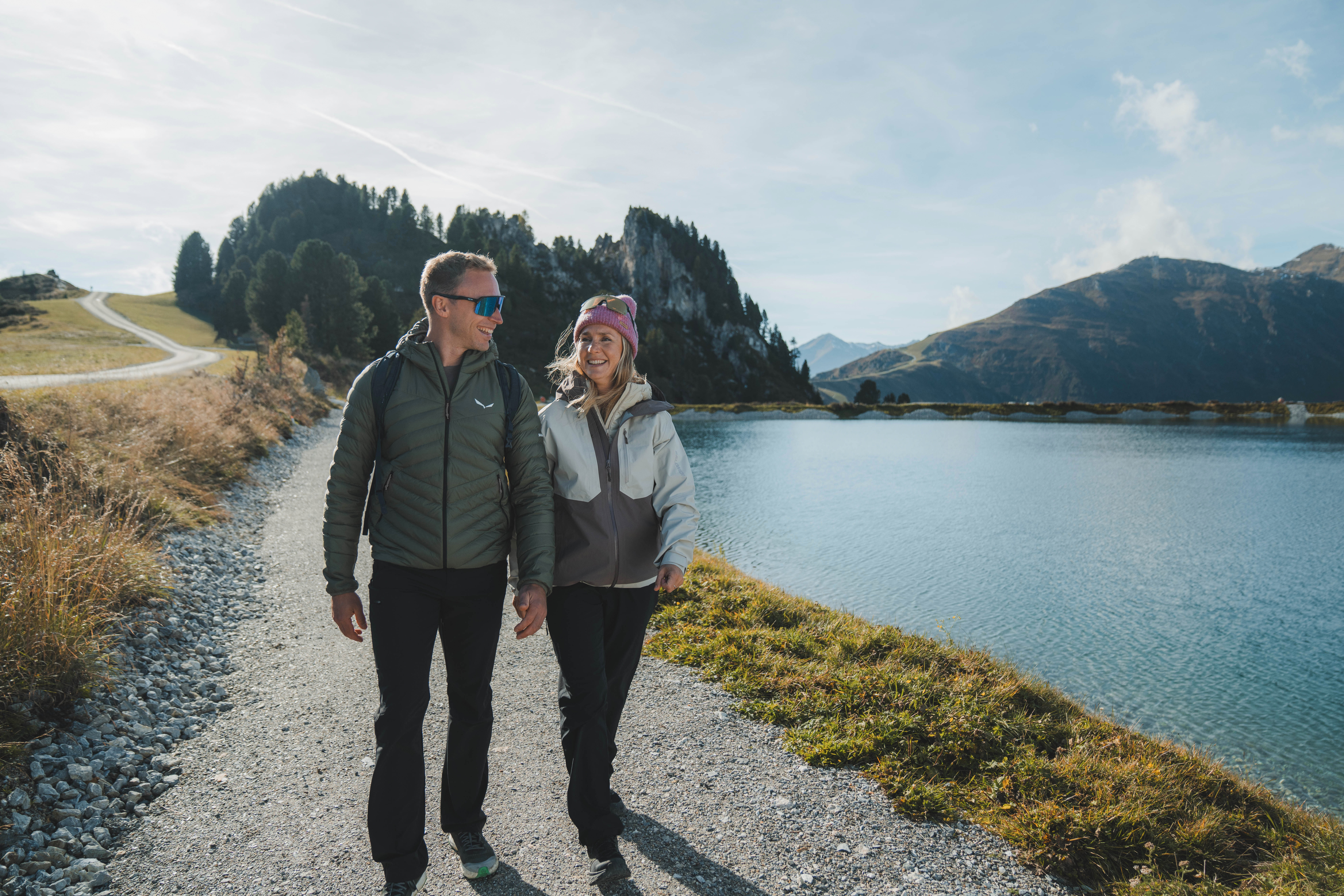 A couple takes an autumn hike in the Mayrhofen mountains with a lake in the background.