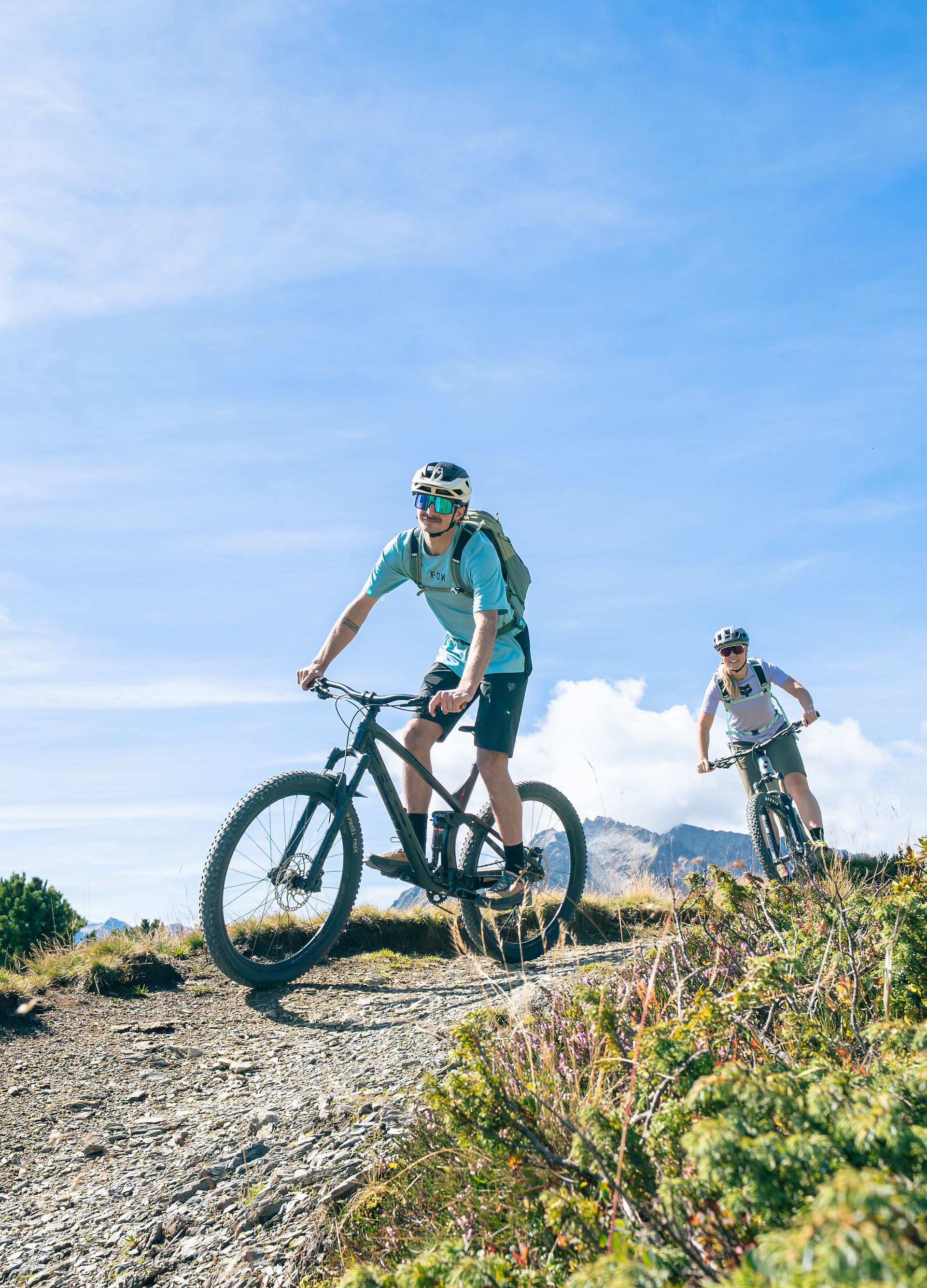 Mountainbiken am Penken bei Mayrhofen-Hippach: zwei Personen stehen mit ihren Bikes auf einem Aussichtspunkt und blicken über die alpine Landschaft mit Bergen und blauem Himmel.