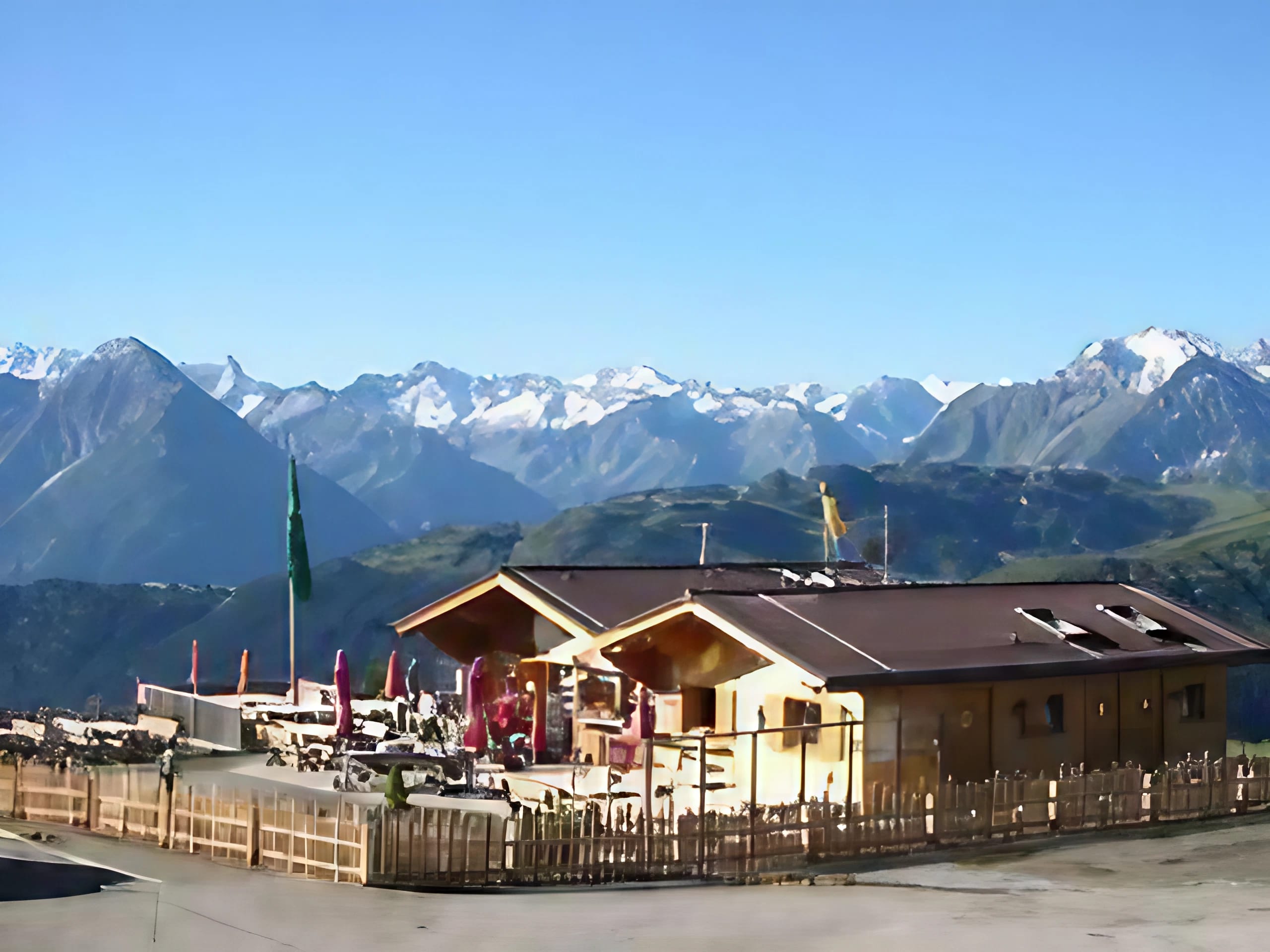 Das Bild zeigt die Jausenstation Melchboden am Schwendberg mit Terrasse und einem Bergpanorama im Hintergrund.