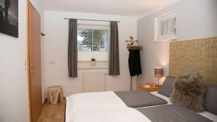 A bedroom with a bed, nightstand, lamp, window, curtains, and wall art.