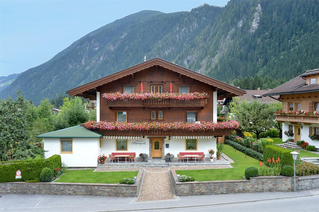 Häuser in einer bergigen Landschaft, mit Blumen geschmückten Balkonen und gepflegtem Garten im Vordergrund.